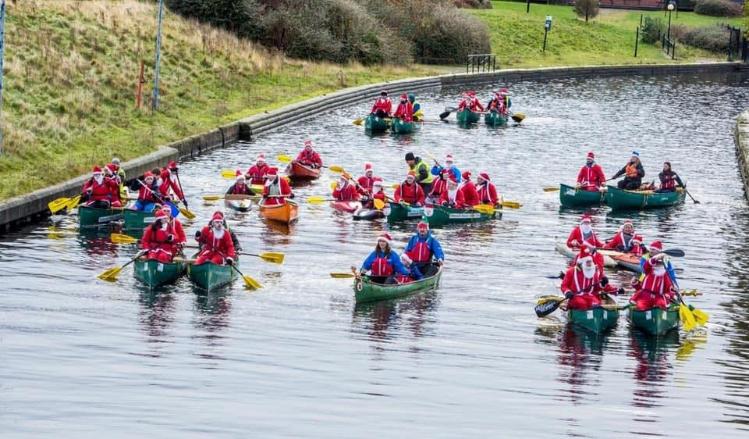 People on kayaks on a canal dressed as santa