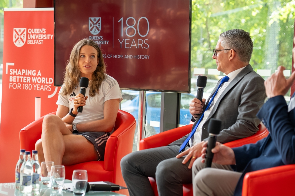 young seated woman speaking into a microphone whilst being interviewed