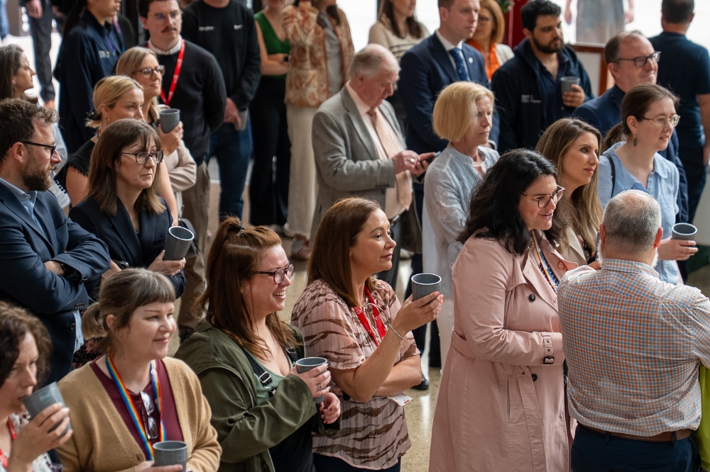 people standing, smiling, chatting, drinking at an indoor event