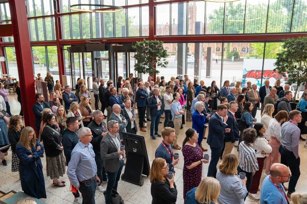 large group of people gathered in a glass-fronted auditorium