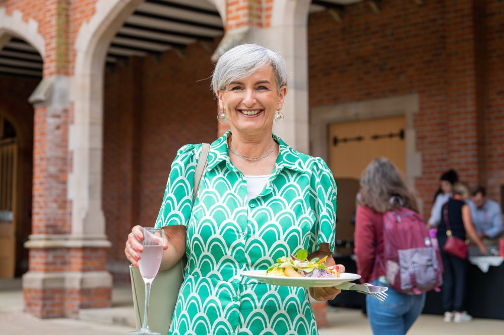 smiling female member of staff holding food and refreshment on the quad