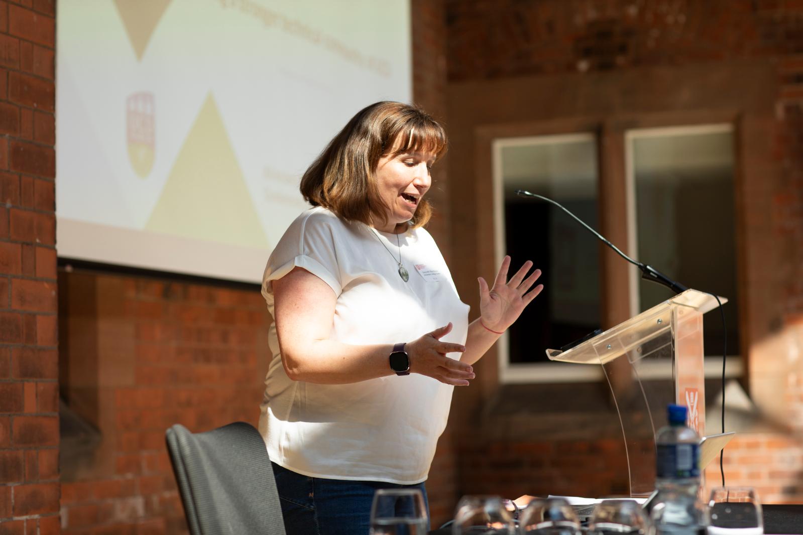 A group of people stand posed beside a portrait in a university grand hall, looking towards the camera.
