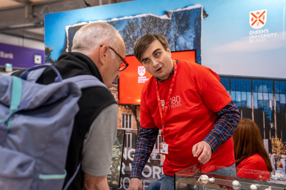 young man in red t-shirt chatting to an older man visiting an exhibition stand