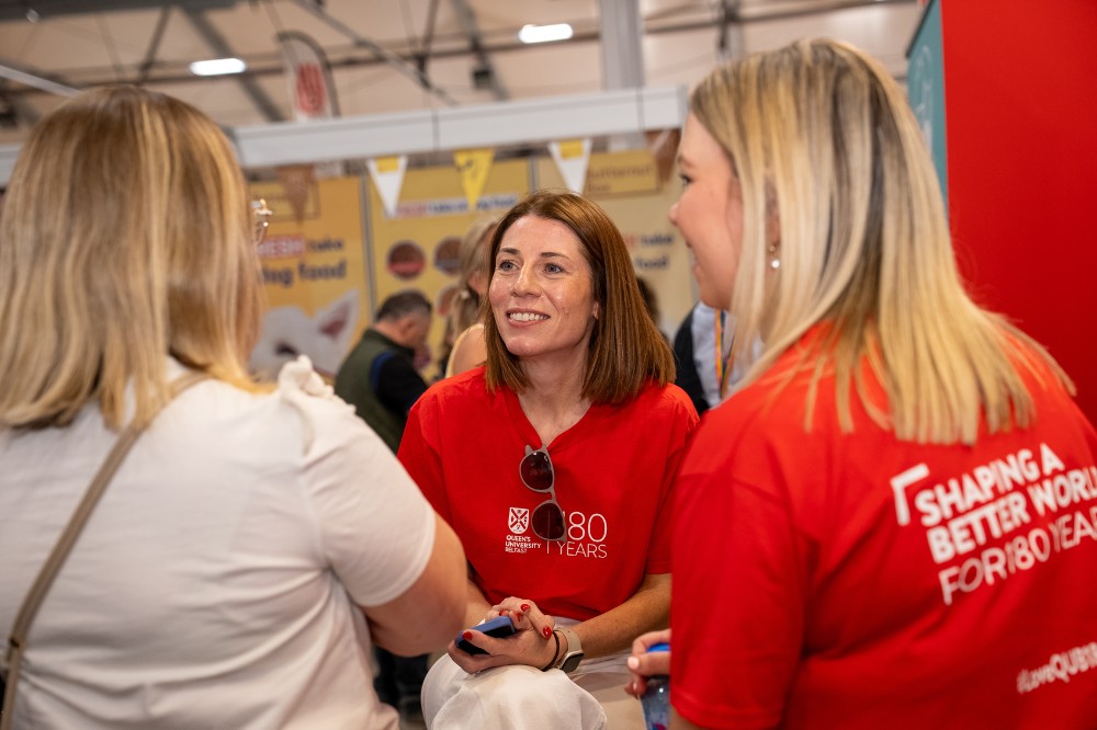 three women talking in an exhibition space