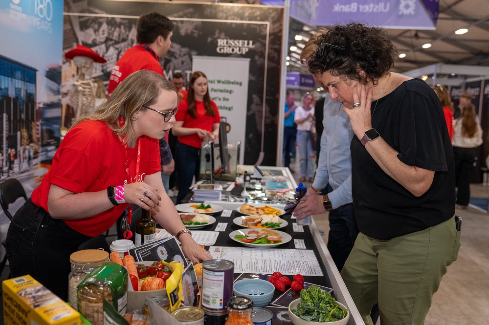 young woman in red t-shirt showing information to passers-by at an exhibition stand