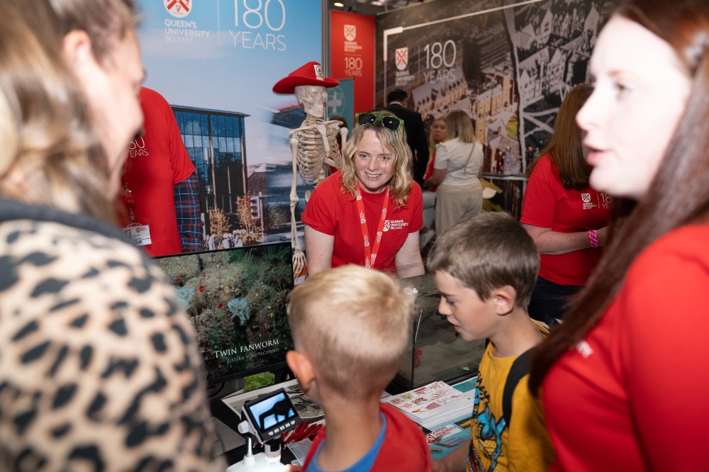 two women chatting and another woman in red t-shirt demonstrating at an exhibition stand