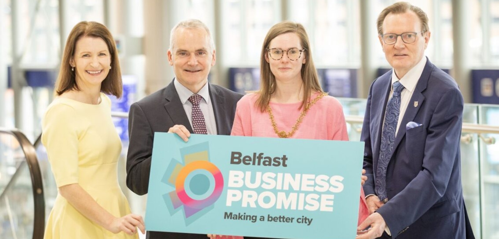 Two men and two women hold a large placard which reads Belfast Business Promise, making Belfast a better city