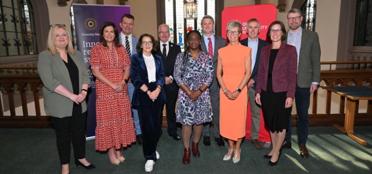 group of people smiling to camera on a balcony in an old building with a stained-glass window in the background