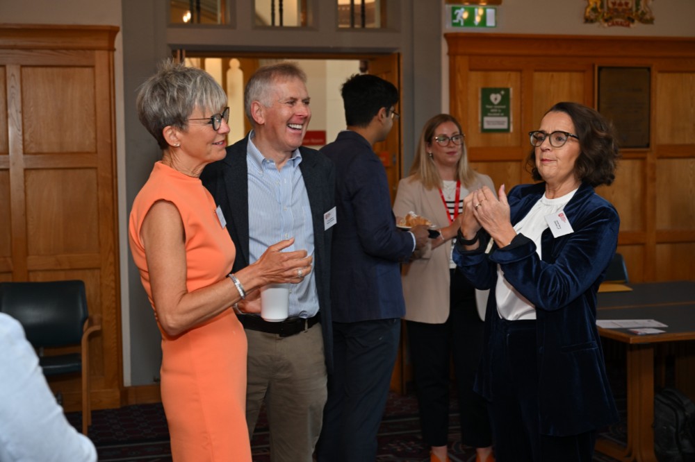 two women and a man chatting and laughing over coffee in an old meeting space