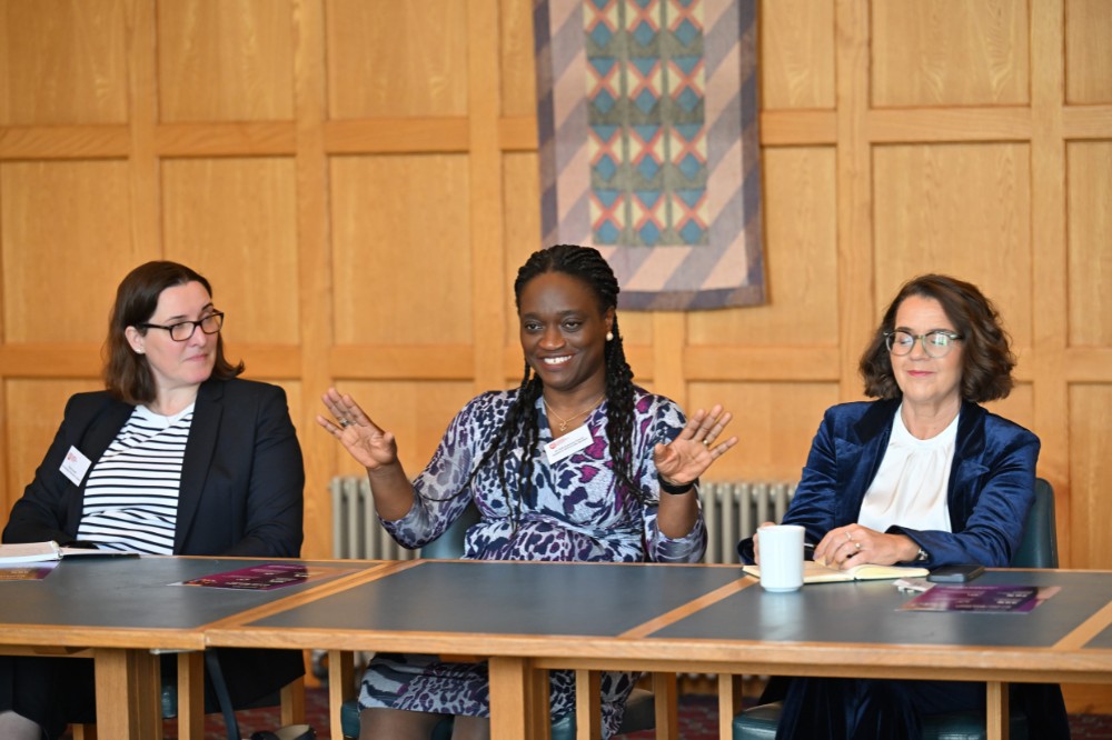 professional-looking female leader talking in a seated boardroom setting, framed by two other women