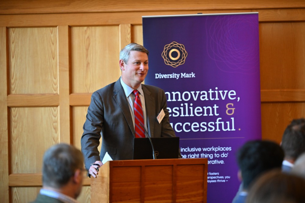 professional-looking man talking to a group in a seated boardroom setting