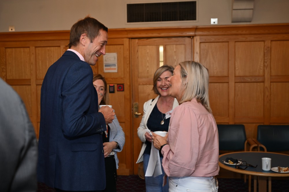 three people chatting happily over coffee in a meeting space