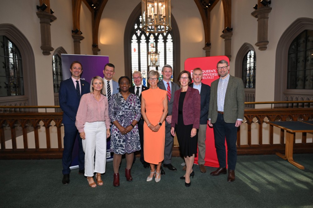 group of people smiling to camera on a balcony in an old building with a stained-glass window in the background