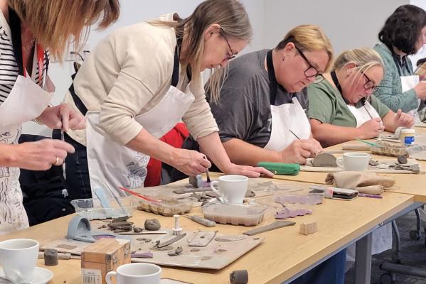 Five aproned staff working with clay.