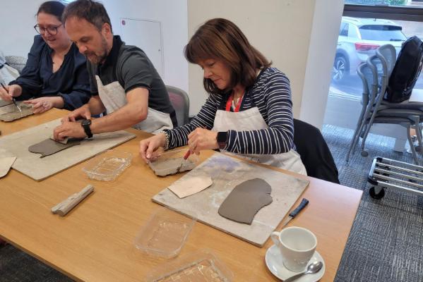Staff using cutting tools on their flat clay artifacts