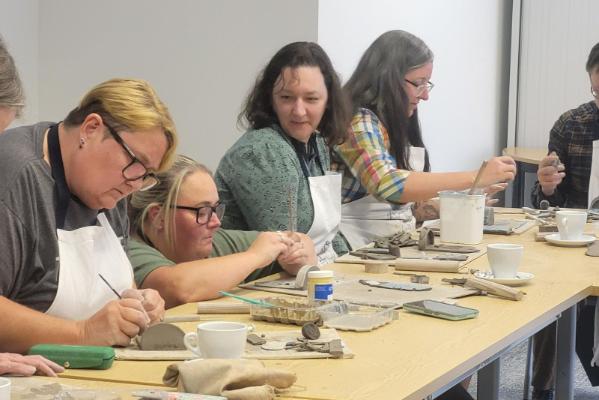 Female staff sitting working on clay rectangular pieces