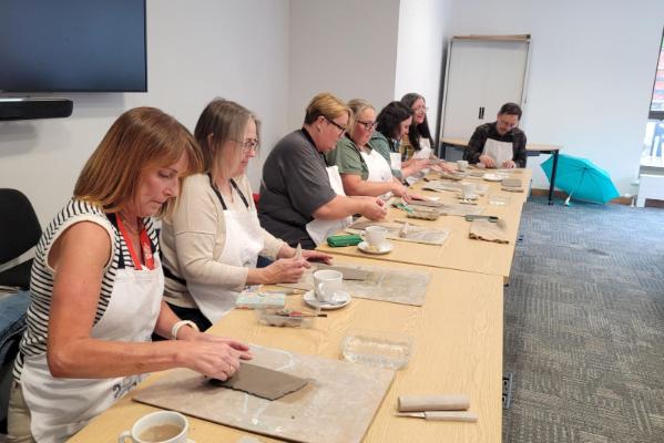 Staff at tables working on rectangular clay flat blocks