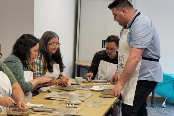 Staff working on their clay creations, under watchful eye of instructor