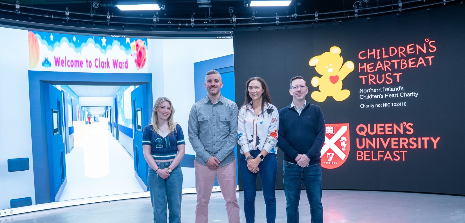 A row of people standing in front of the screens in the Media Lab at Queen's.