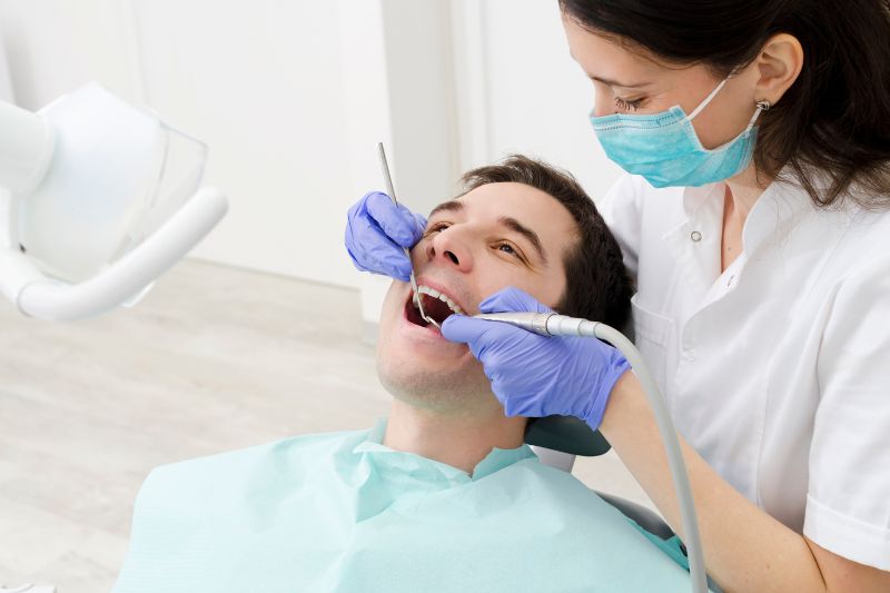 Female dentist performing dental treatment on male patient