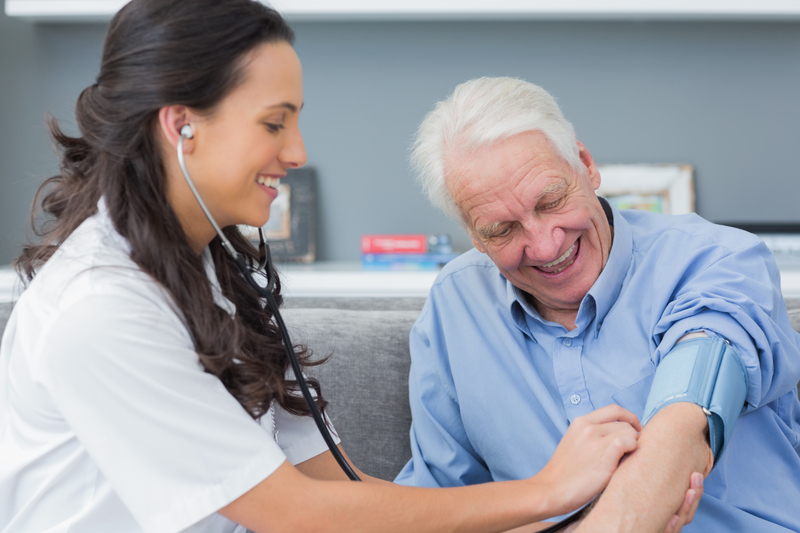 Female doctor measures blood pressure of elderly man