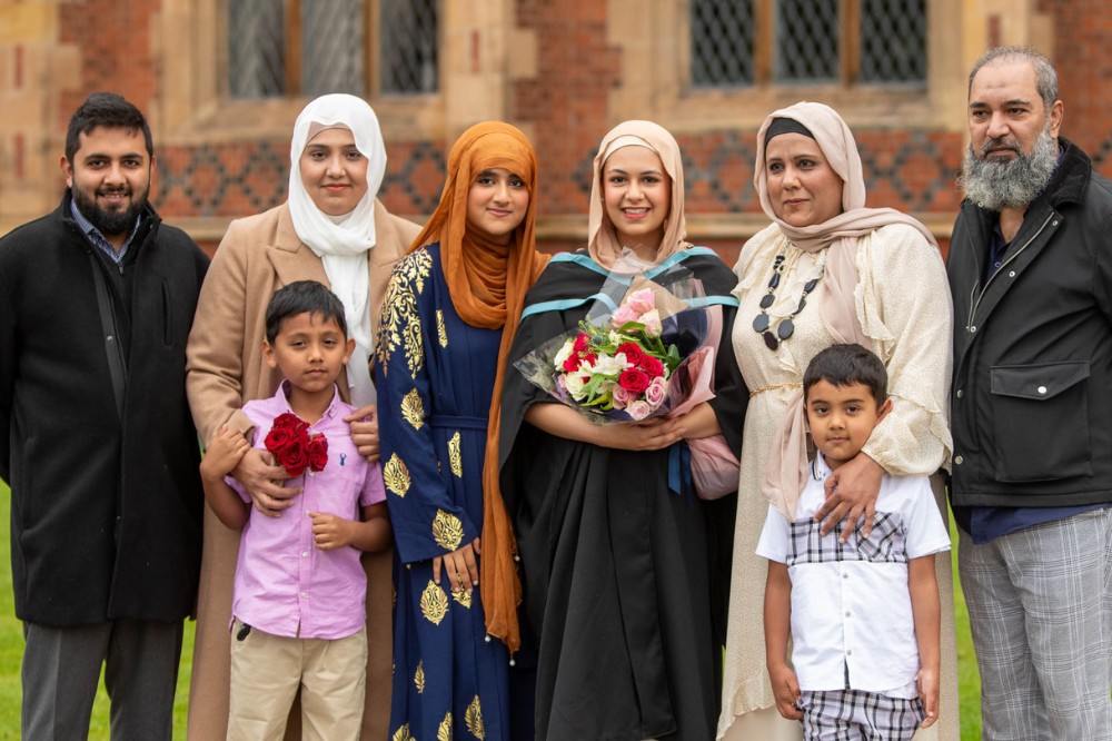 family of South Asian origin posing for a graduation photo outside a redbrick building