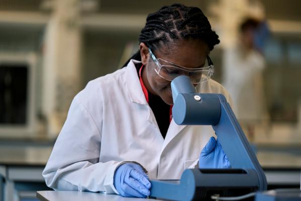 Researcher wearing lab coat looking through microscope