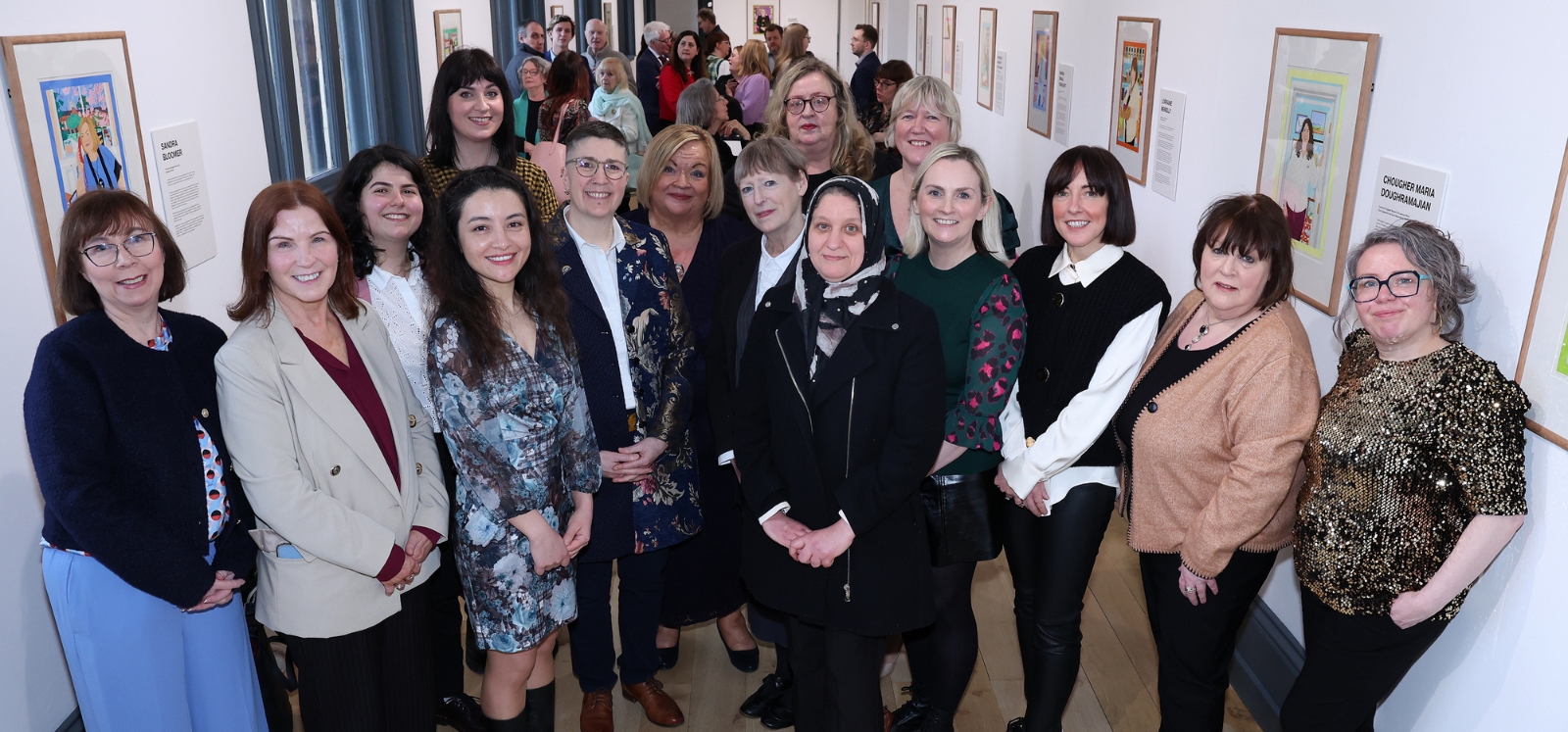 A group of women standing together smiling in the Naughton Gallery to mark the launch of 'IN GOOD COMPANY: Portraits of Queen’s Women'