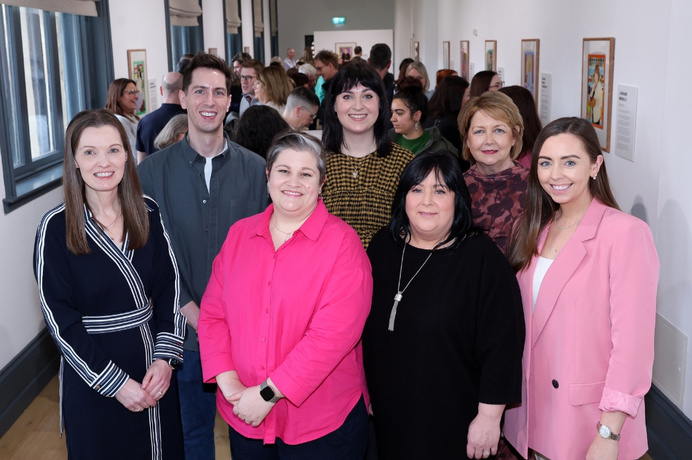 A group of smiling women standing in the Naughton Gallery to mark the launch of the Portrait Illustration Project