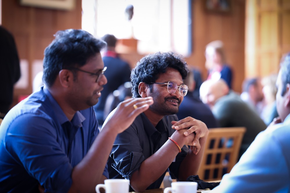 two men of South Asian origin seated and enjoying conversation in an indoor event