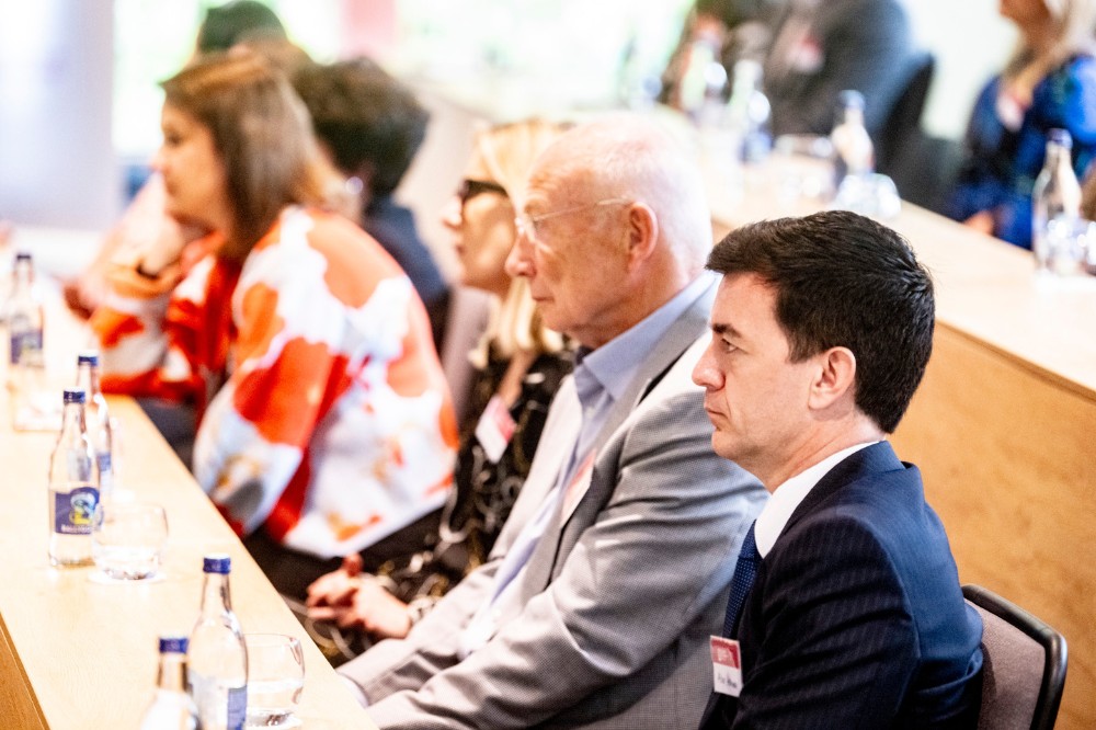 serious-looking people sitting, listening and watching in a bright lecture space
