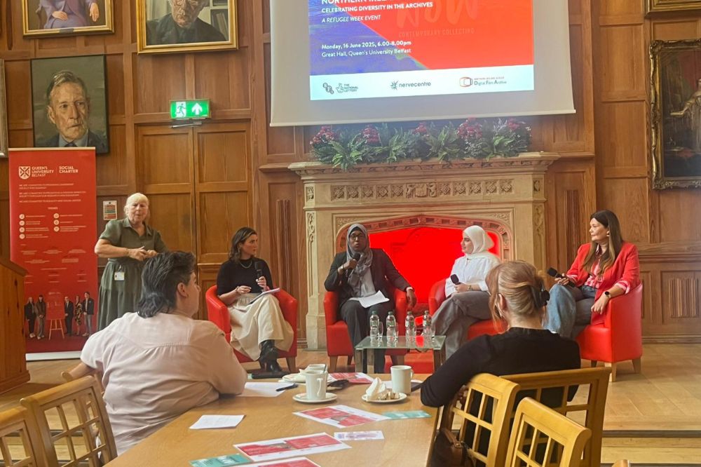 Four females sitting down in red chairs in a fireside chat orientation with a female sign interpreter