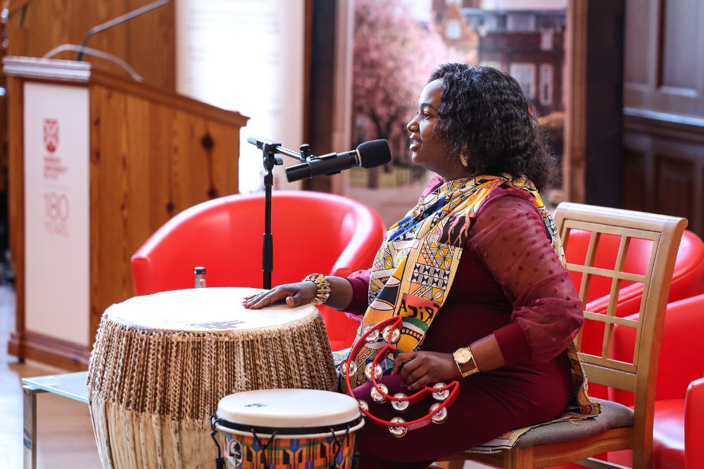 Seated lady singing and playing traditional african site bongo drums