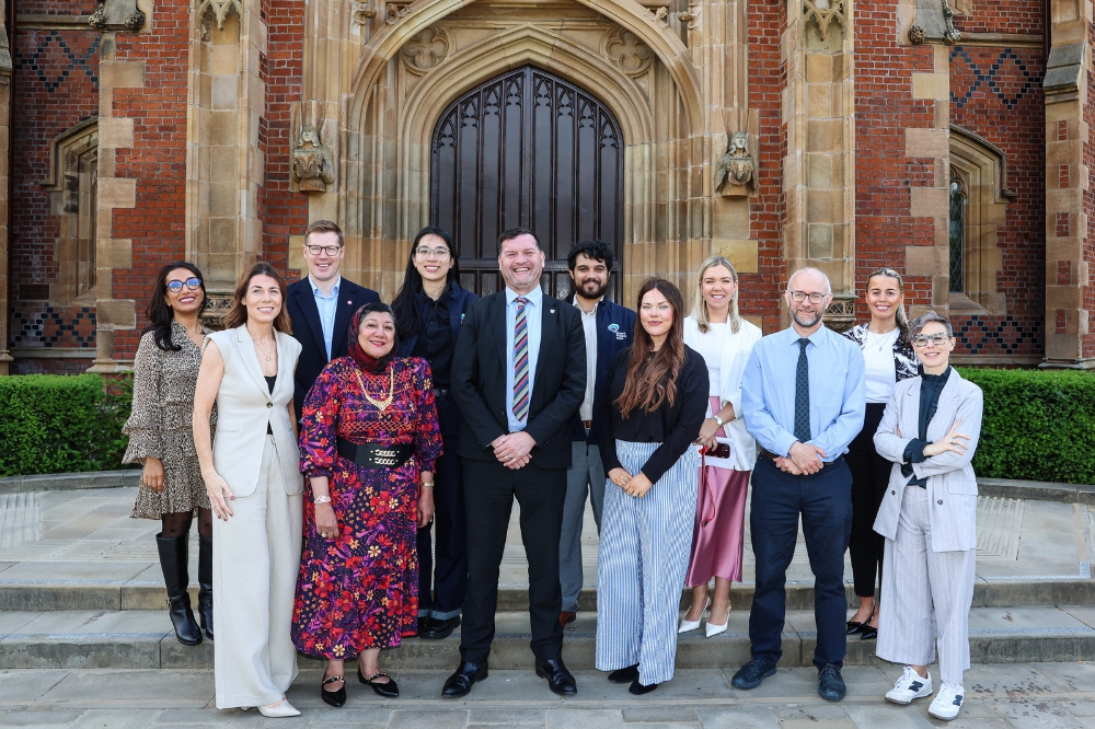 Queen's staff and students standing outside the Lanyon Building celebrating the University's newly awarded Sanctuary Status