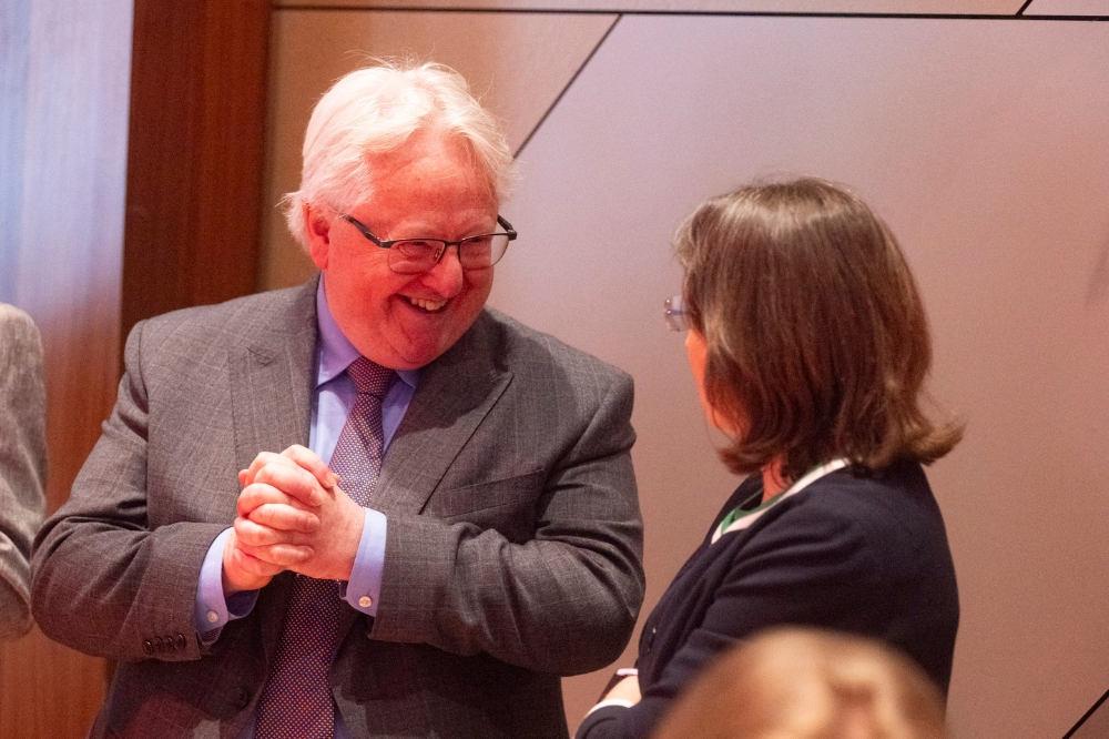 suited older professional man laughing with female colleague