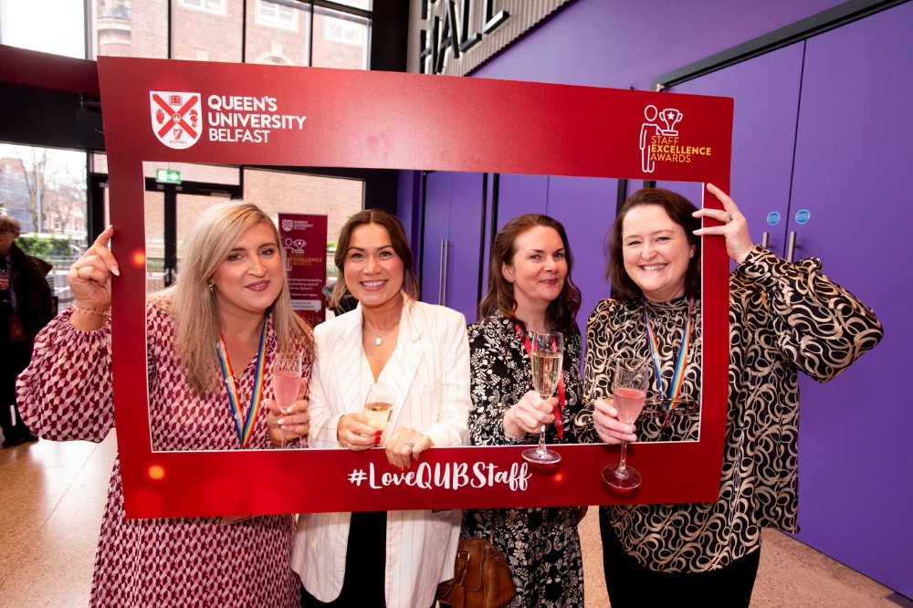 four women pose with a red foamboard photo frame at Queen's Staff Excellence Awards 2023-24