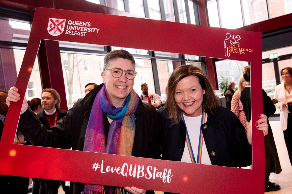 two women pose with a red foamboard photo frame at Queen's Staff Excellence Awards 2023-24