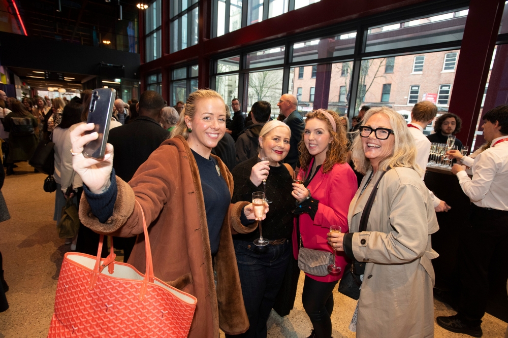 group of people - one holding a camera for a selfie - smiling outside Mandela Hall, Queen's University Belfast