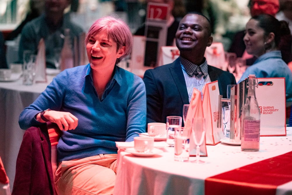 people laughing at a dinner table at a gala event