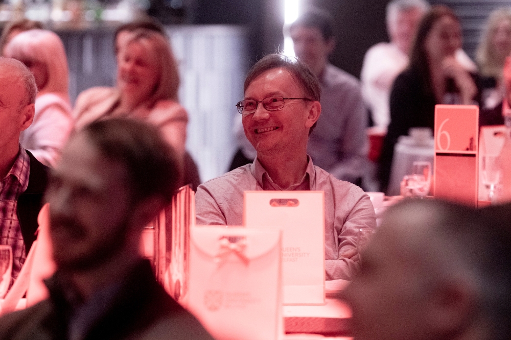 man laughing at dinner table at gala event