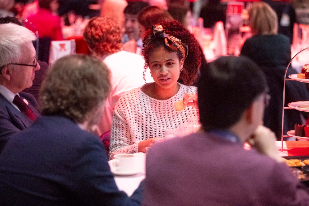 people sitting and chatting at a round dinner table in an event hall