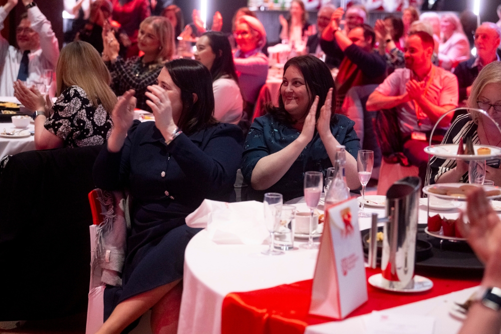 seated group of people smiling and applauding at a gala event